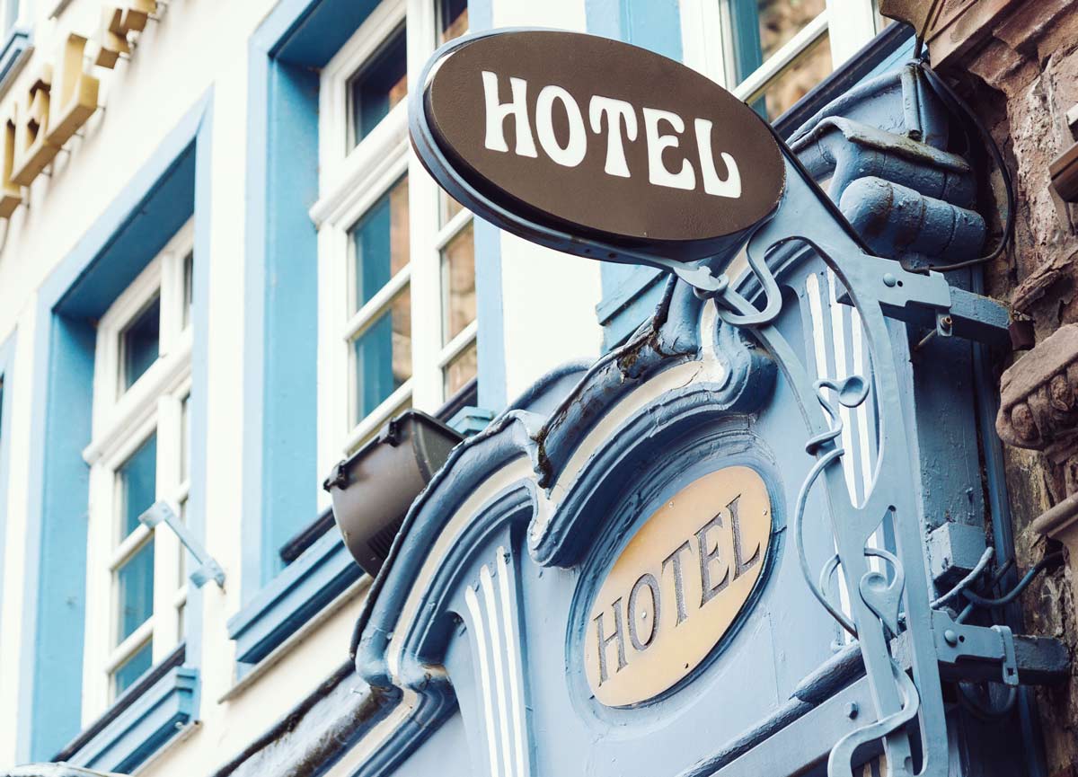 Elegant outdoor hotel sign with black, white, and blue design with two signs one black and white and the other blue and beige saying “Hotel”.